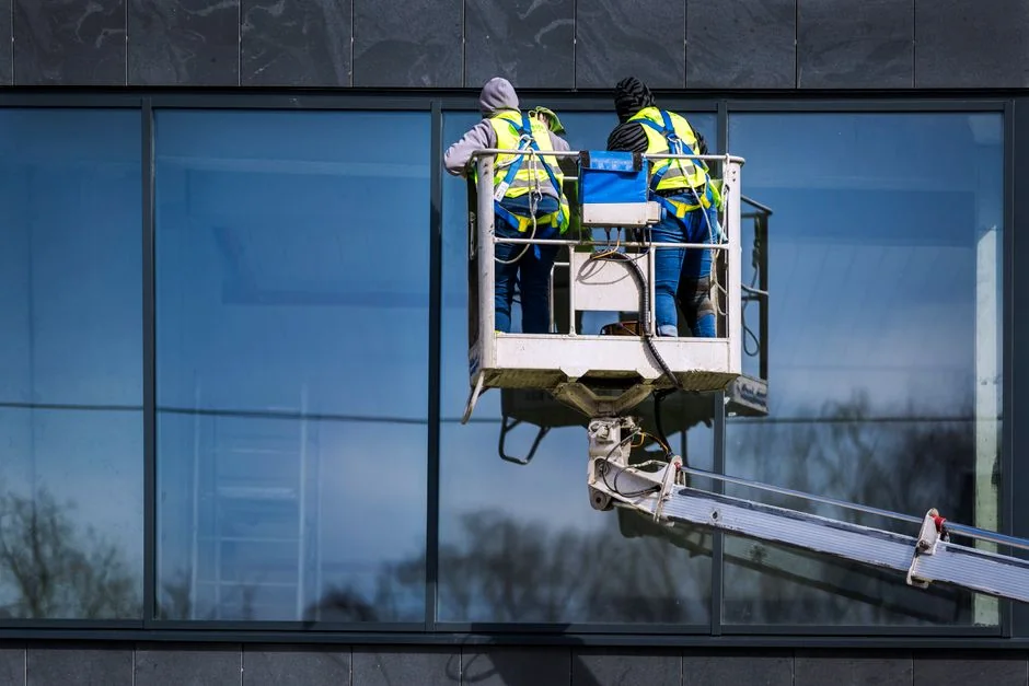 A man cleaning skyscraper windows with a harness, showcasing urban high-rise work.